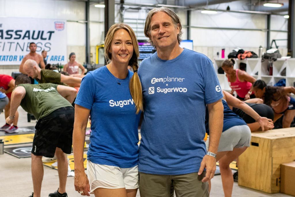 Shayna and Drew Larsen of the coaching software company SugarWOD pose in blue T-shirts.