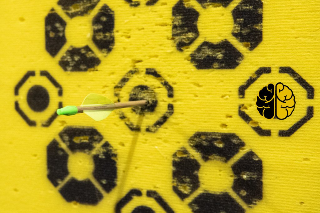 An arrow is buried deep in the bull's eye of a black and yellow archery target.