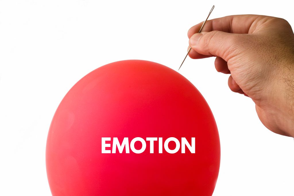 A hand holding a needle prepares to pop a bright red balloon labeled "emotion."