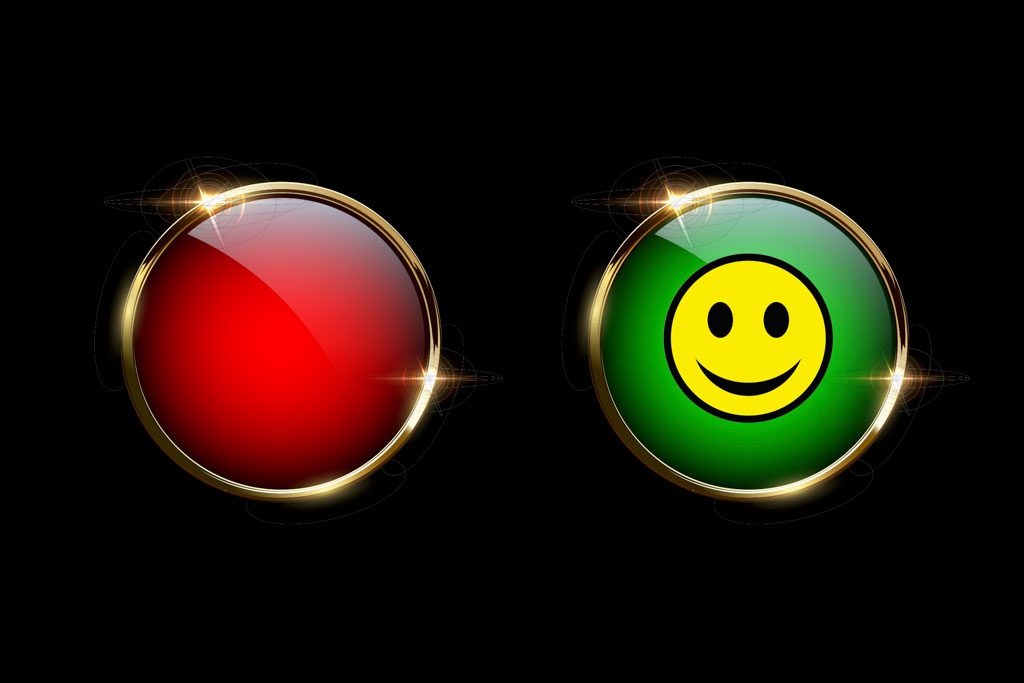 On a black background, a shiny red button and a bright green button with a yellow smiley face on it.