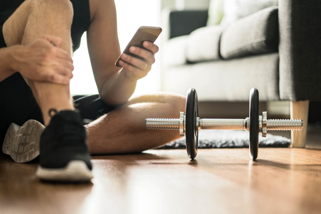 Man using smartphone during workout at home.