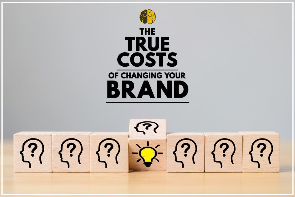 Wooden cubes decorated with question marks, one is flipped over to reveal an 'idea' lightbulb - The True Costs of Changing Your Brand