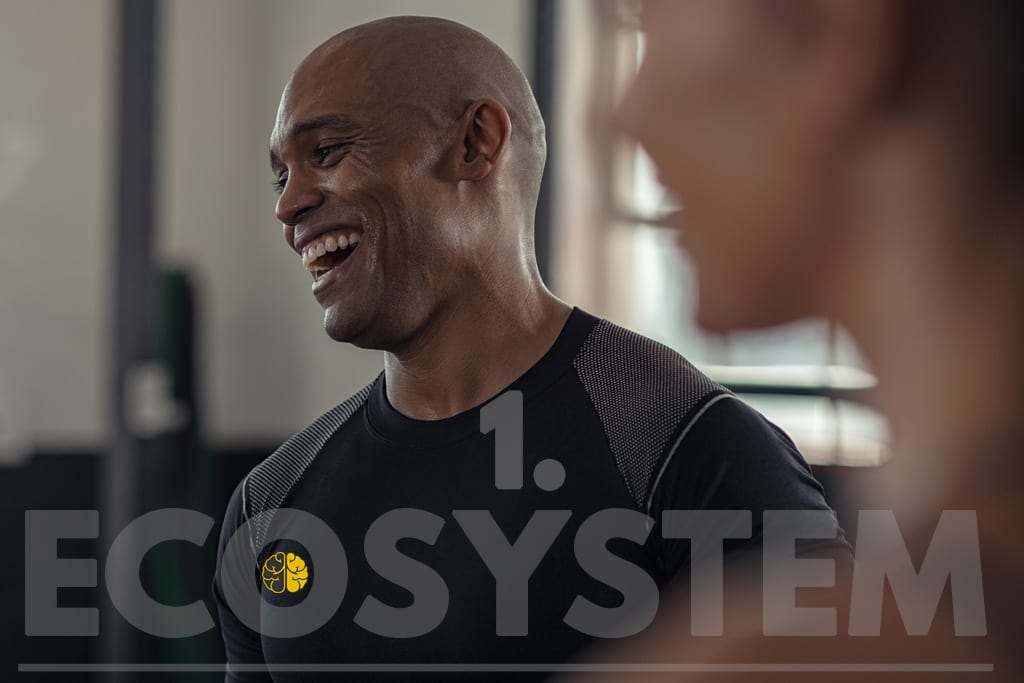 A man smiling with friends at a Crossfit gym - Ecosystem