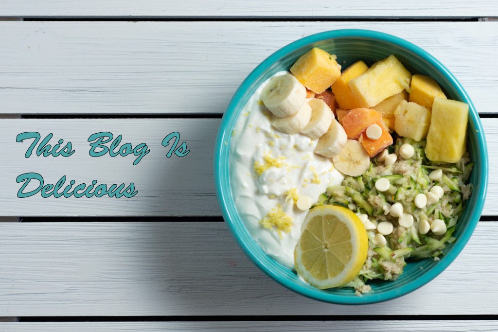 A bright blue bowl full of yogurt and fruit with the words "this blog is delicious" beside it.