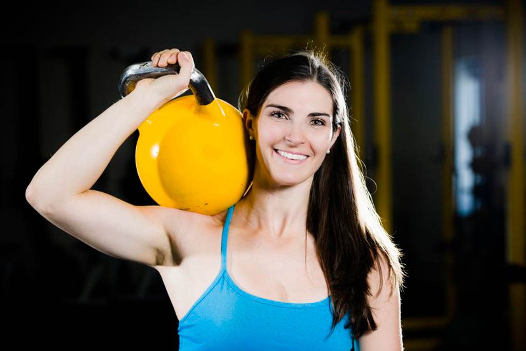 A portrait head shot of registered dietitian Jen Broxterman holding a yellow kettlebell.