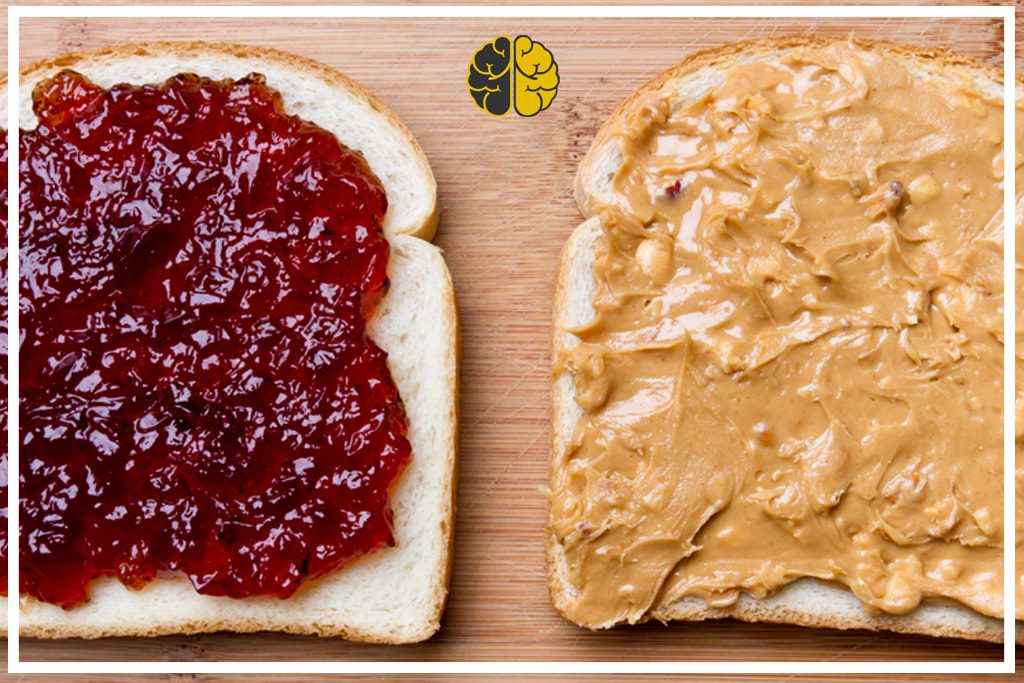 Two pieces of bread, one with peanut butter, the other jam