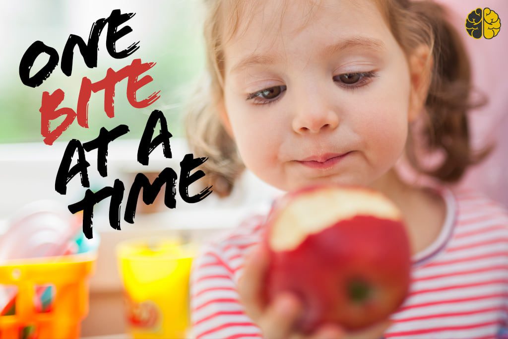 A young girl about to take a bite of an apple - one bite at a time