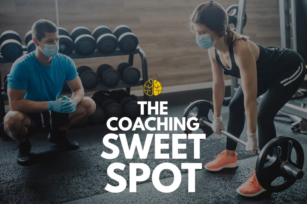 A coach in a face mask assisting a client with a lift - the coaching sweet spot