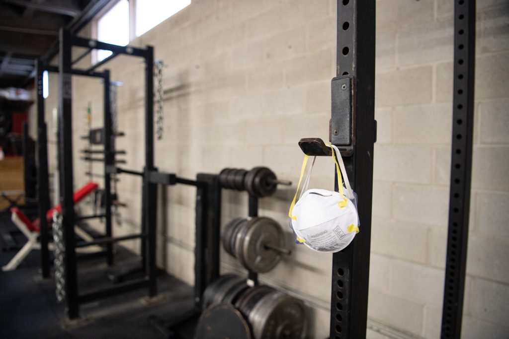 An N95 mask hangs on a squat rack in a gym during the COVID-19 pandemic.