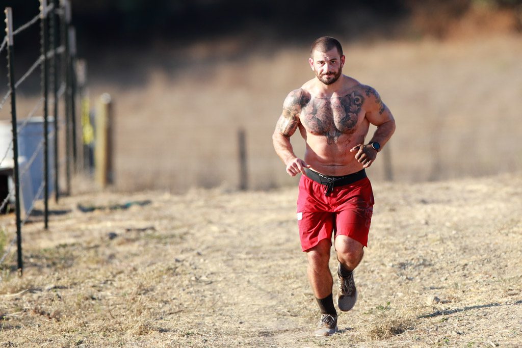 A determined and shirtless Mat Fraser runs in the dust at the 2020 CrossFit Games.