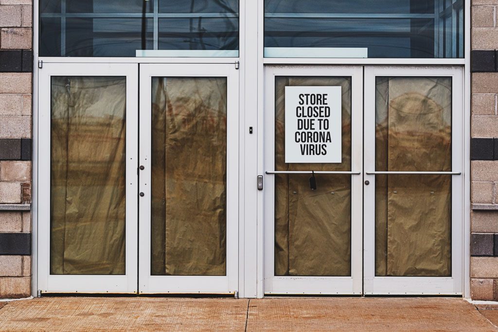 A business storefront with paper on the windows and a sign that says "closed due to coronavirus."