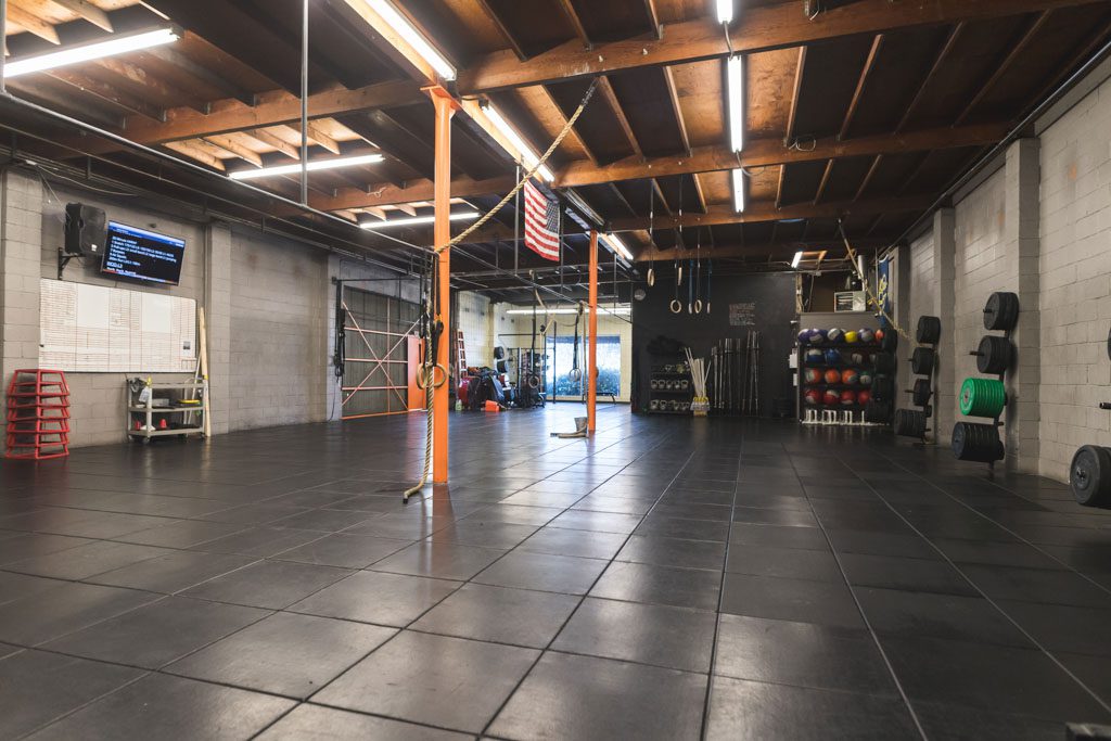 An empty functional fitness gym with rings, plyo boxes and other equipment.