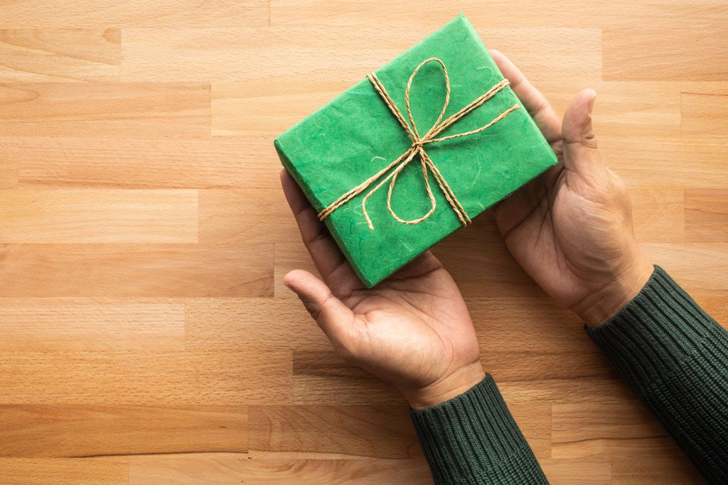 A closeup of a gym owner's hands holding a gift wrapped in green paper.