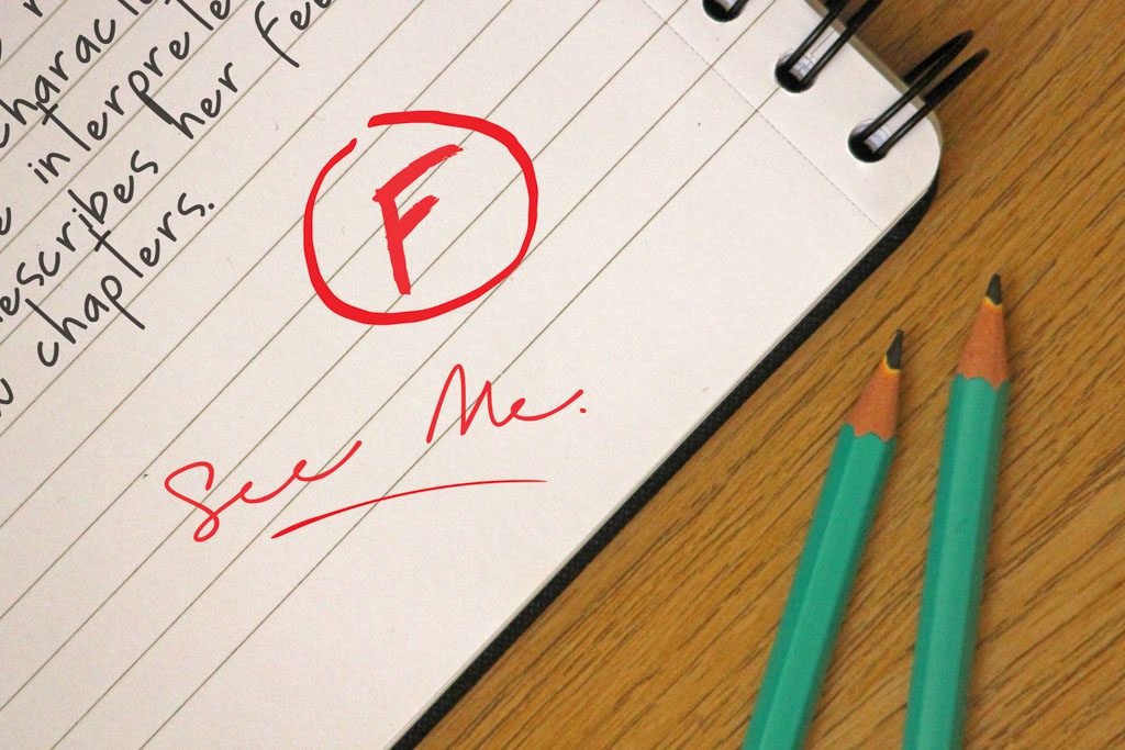 A closeup of a report card with a large red "F" and the words "see me."