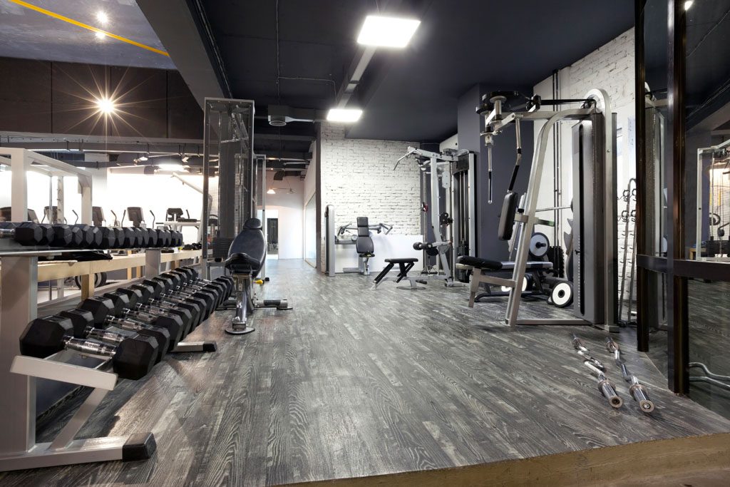 A photo of an empty gym with a dumbbell rack and various fitness machines.