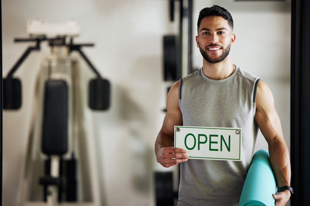 A fitness entrepreneur welcomes clients into a weight room after opening a gym.