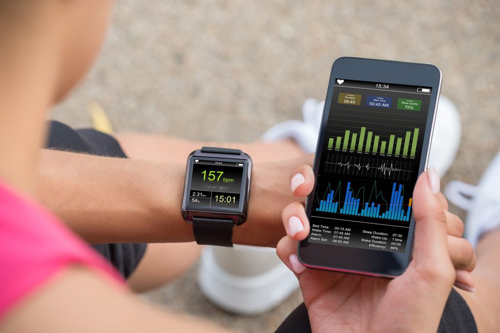 A closeup image of a watch and a connected smartphone with fitness tracking data.