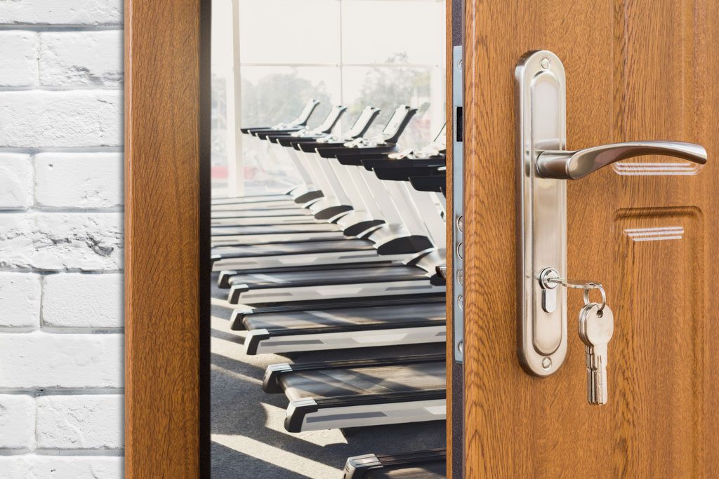 How to start a gym: A peek inside a gym door with a key in its lock.