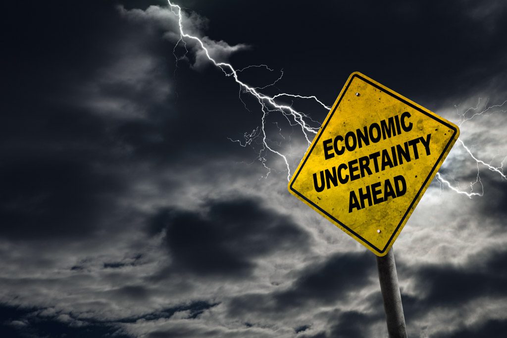 With a stormy sky above, a yellow roadside reads "economic uncertainty ahead."