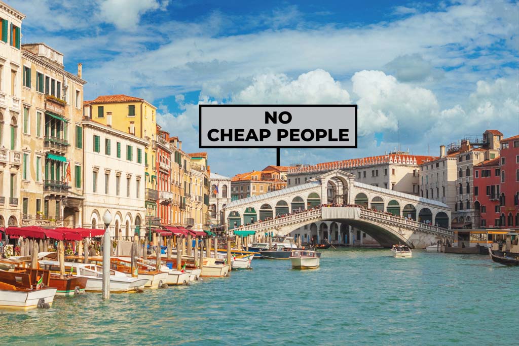 A landscape shot of Venice, Italy, with a billboard that reads "no cheap people."