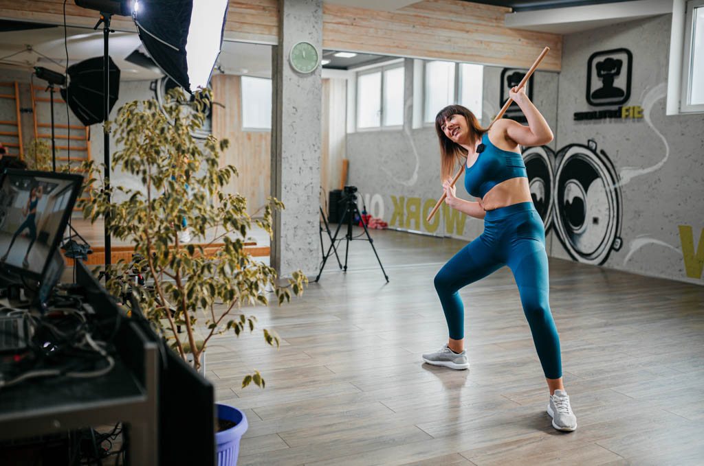 A social media influencer films a workout video in a gym.