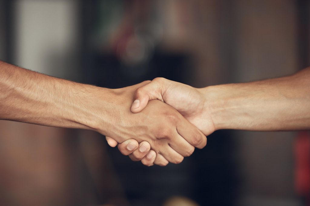 A closeup of two people shaking hands in a gym.