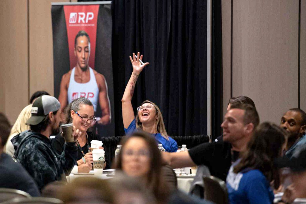 A fitness coach at the Two-Brain Summit raises her hand to celebrate an epiphany.