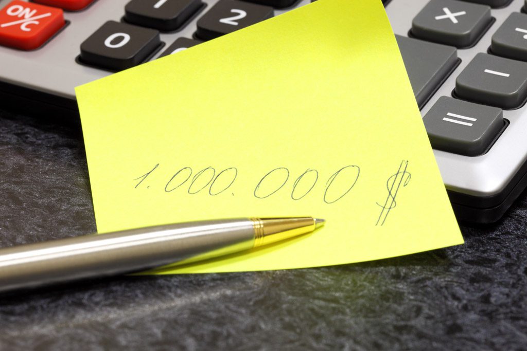 A yellow sticky note beside a calculator with "$1 million" written on it.