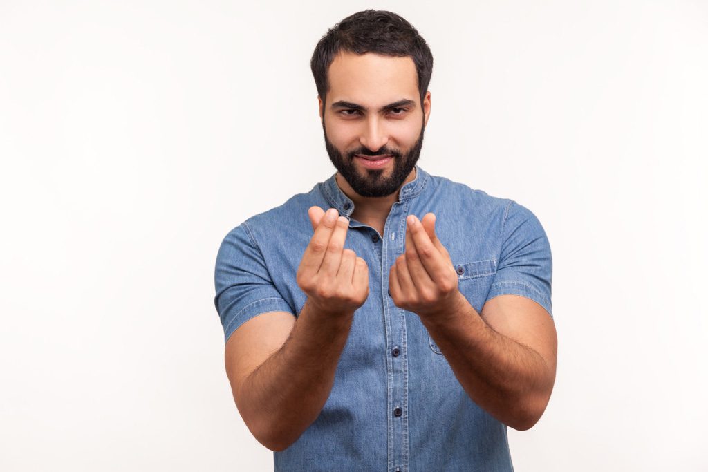 An entrepreneur with large biceps looks at the camera and rubs his fingers together to suggest "money."
