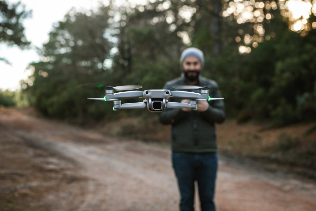 A gym owner holds a remote control and pilots and airborne drone.