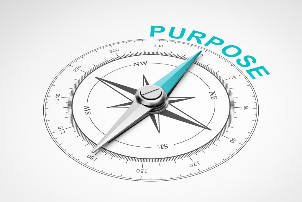 A closeup image of a compass with the needle pointing north to the word "purpose."