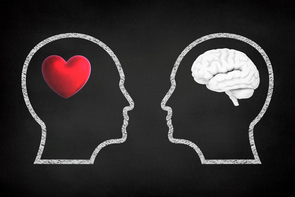 A chalkboard drawing of two outlined heads in conversation—one contains a brain and the other contains a heart.