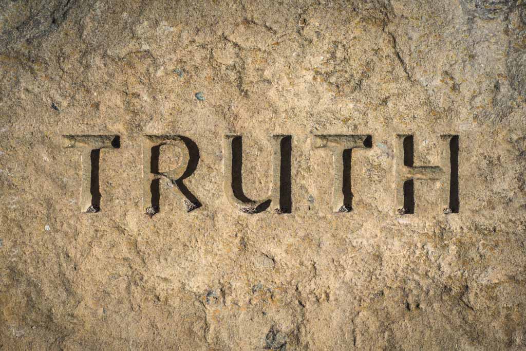 A closeup image of the word "truth" chiseled into marble.