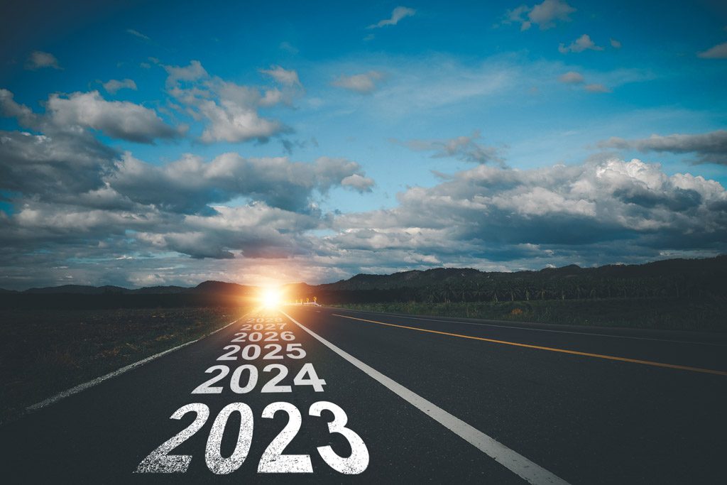 A highway leads toward a sun rising above the horizon, with the numbers 2024 and 2025 on the asphalt.