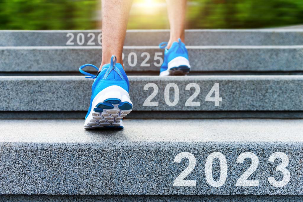 A closeup image of a person running up stairs labeled "2023" to "2026."