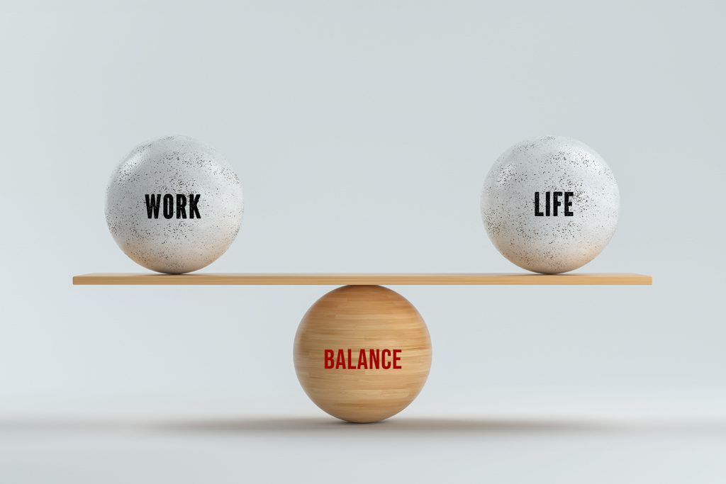 Two stones balanced on a beam over a third stone, with the top two labeled "work" and "life" and the bottom labeled "balance."