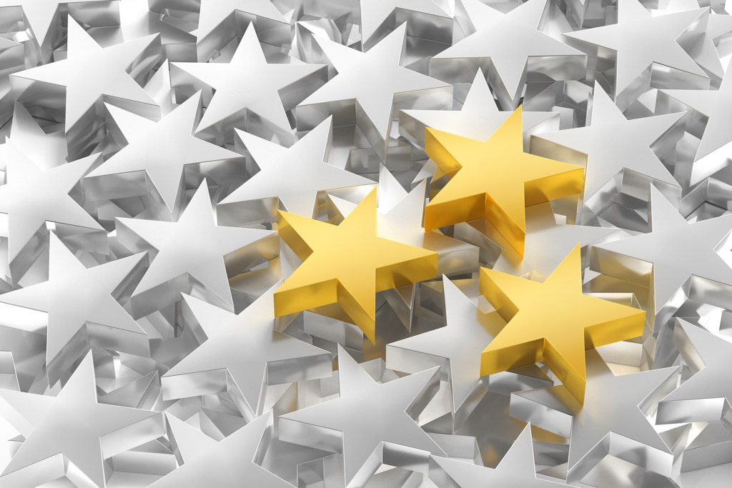 In a pile of silver stars, three gold stars stand out.
