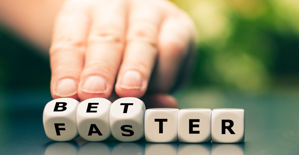 A closeup image of fingers turning a set of lettered blocks to create the words "better faster."