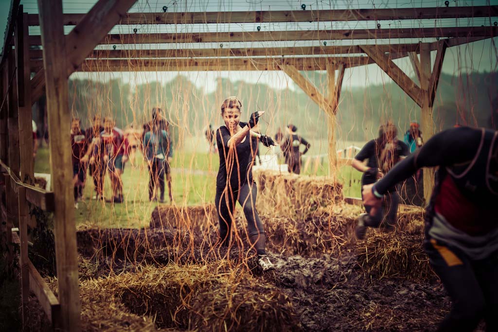 A determined woman running through electrified wires in an obstacle-course race.