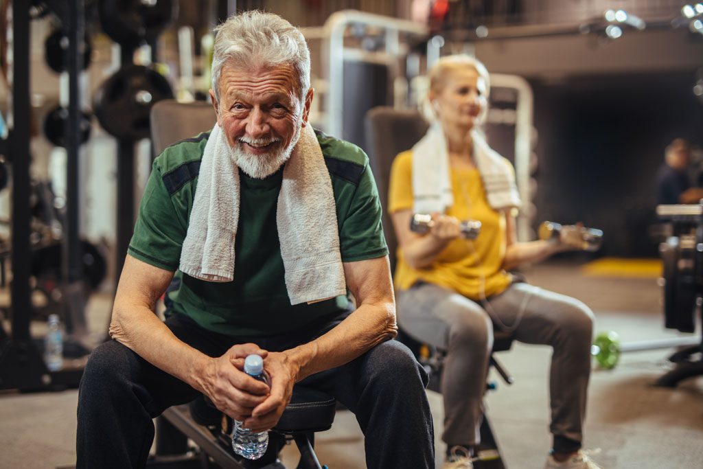 A smiling older man and woman work out in a functional fitness gym.