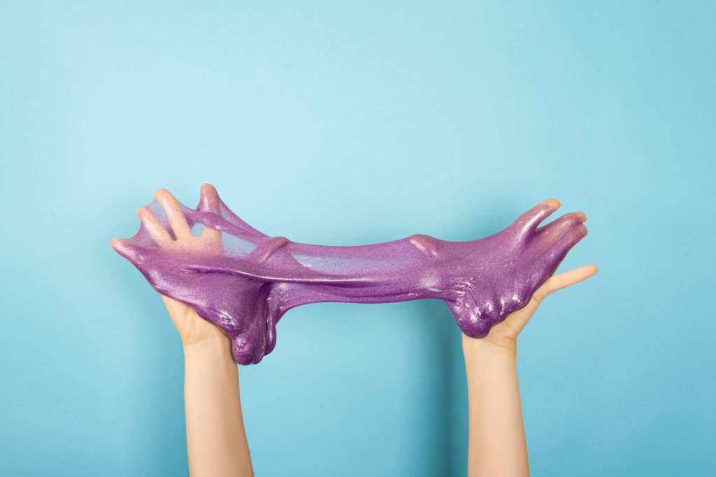 A close-up of two hands covered in thick, purple slime.