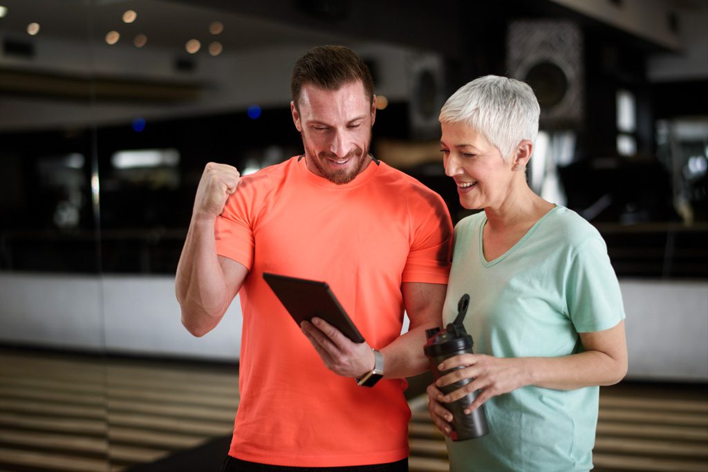 A fitness coach reviews a client's training log and celebrates a great result with her.