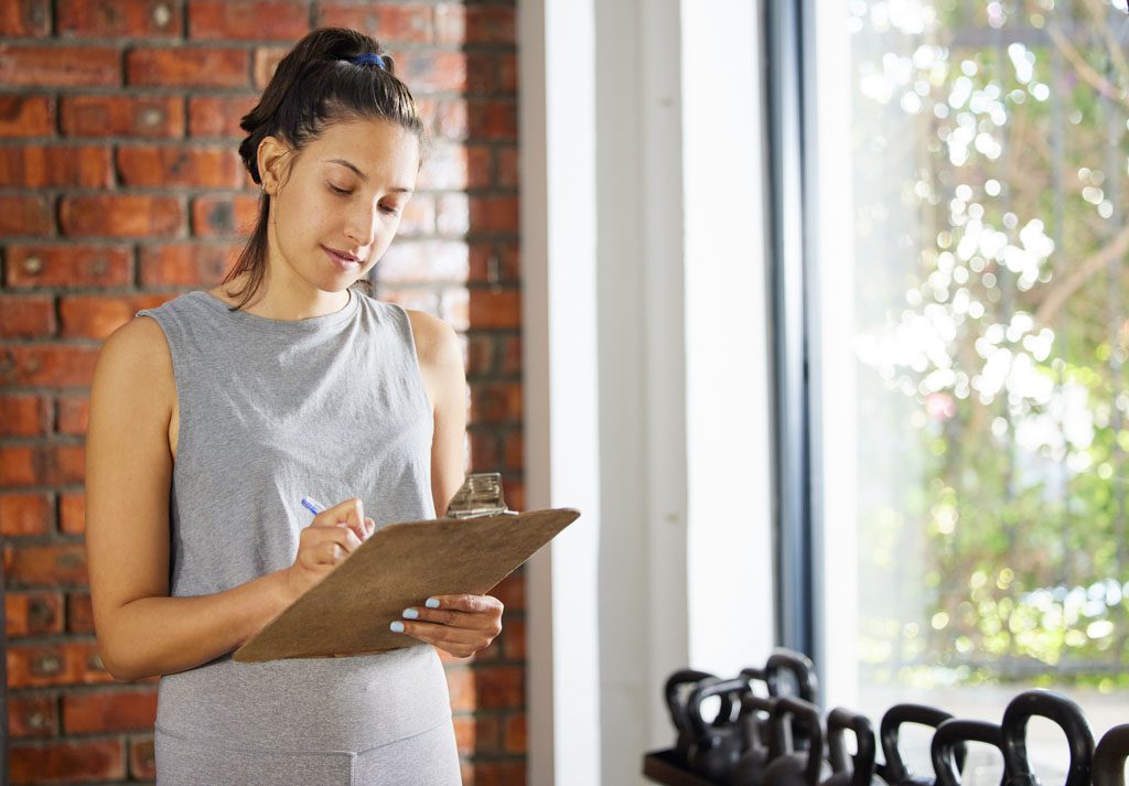 A gym owner with a clipboard fills out a marketing checklist.