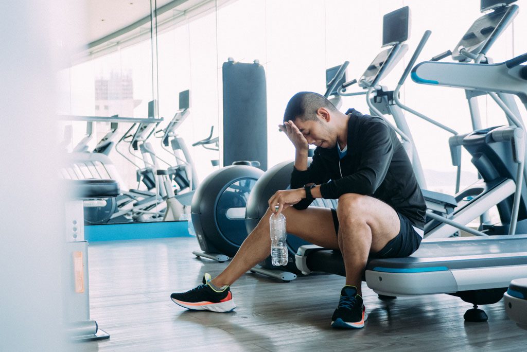 A depressed gym owner slumps on a treadmill because of low summer revenue totals.