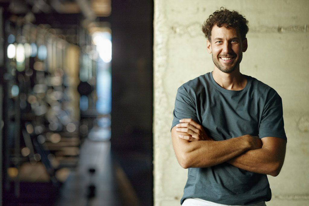 A photo of a smiling gym owner standing inside his facility.