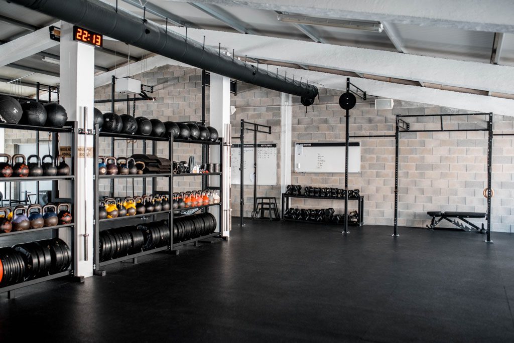 An empty gym with a rack in the middle to create a separate space for semi-private personal training.
