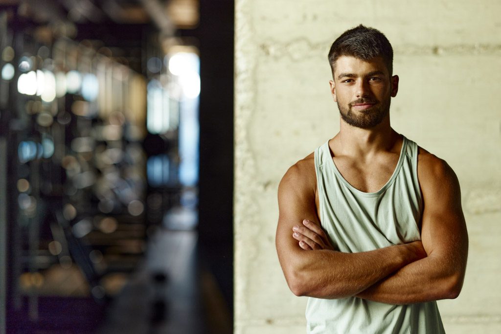 A confident, happy gym owner poses in his facility.