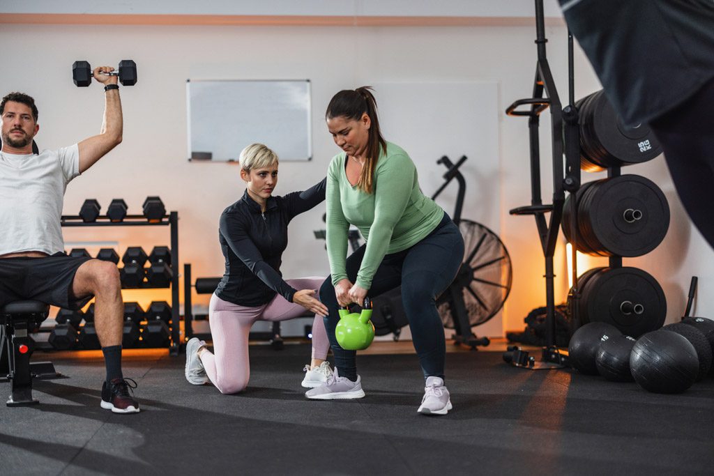 A fitness coach teaches a new client how to perform kettlebell swings.