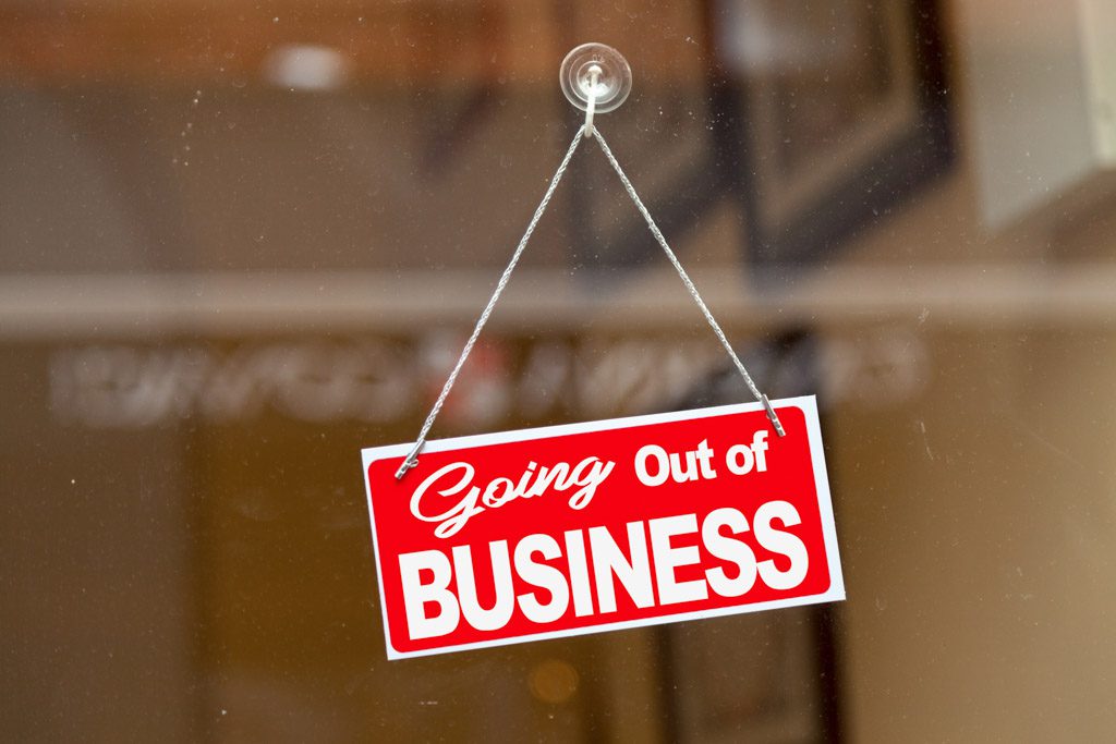 A sign reading "going out of business" hangs in the window of a gym.