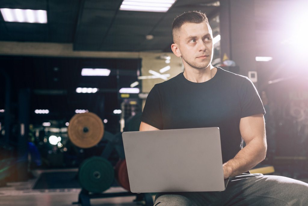 A gym owner uses a laptop to fill out a survey.